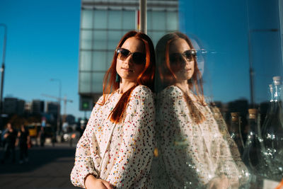 Young woman with sunglasses against city in background