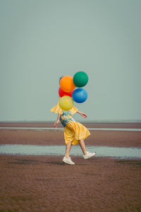 Young woman with colorful balloons at beach