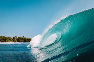 Water splashing in sea against clear blue sky