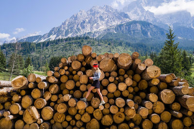 Woman standing on the stack of the tree logs