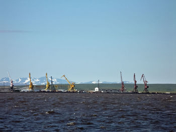 Cranes at commercial dock against clear blue sky