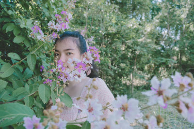 Portrait of woman with pink flowers against plants