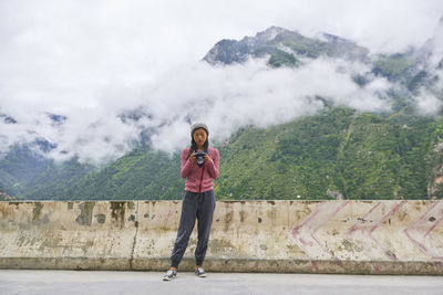 Full length portrait of woman standing on mountain against sky