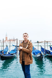 Young blond guy in a brown jacket in middle of streets of venice