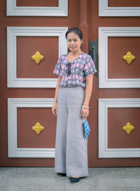 Portrait of beautiful woman standing against closed door