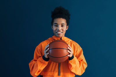 Portrait of young man standing against blue background