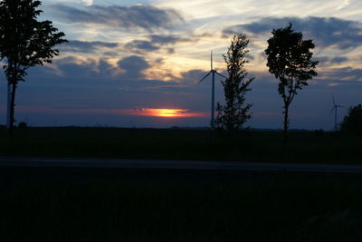 Silhouette trees on field against sky during sunset