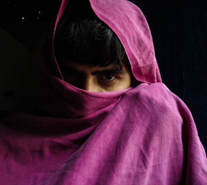 Close-up portrait of woman with pink face against black background