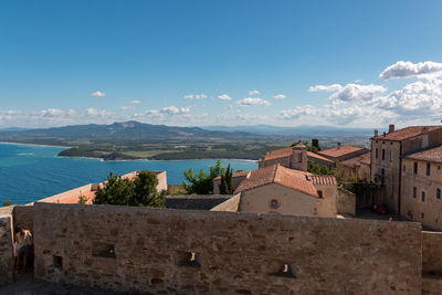 Buildings by sea against blue sky