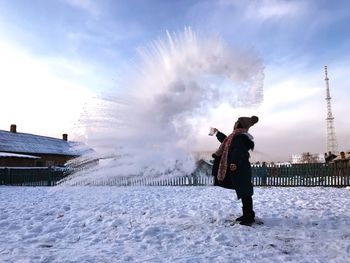 Woman in warm clothing standing on snow against sky