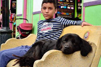 Portrait of boy with dog sitting on bench