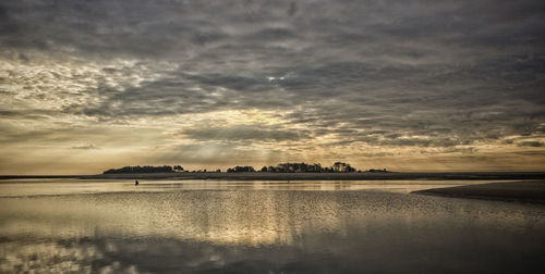 Scenic view of beach against cloudy sky