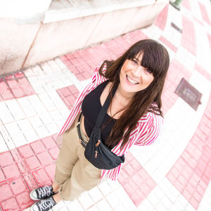 Portrait of smiling young woman standing on pink cobbled street