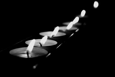 Close-up of illuminated tea light candle in darkroom