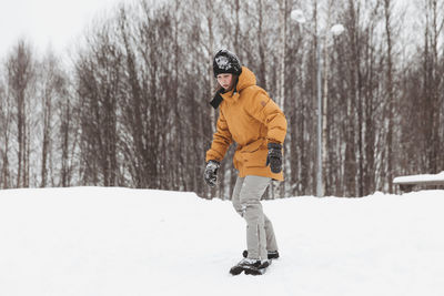 Cute teenage girl rides a snowskate in a winter park, healthy lifestyle