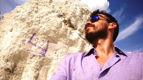 Young man wearing sunglasses against rock