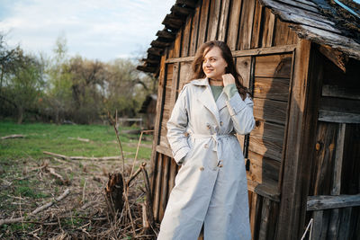 Girl with long hair in a grey trench coat outdoors in spring