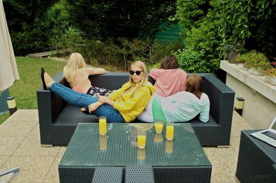 High angle view of friends with juice on table relaxing in yard