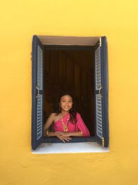 Portrait of smiling girl looking through window