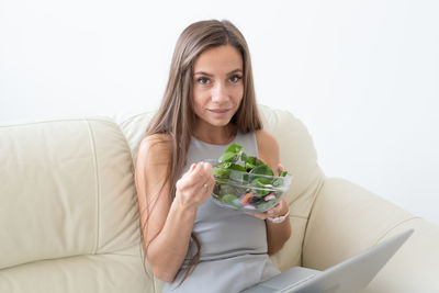 Portrait of a smiling young woman sitting on sofa