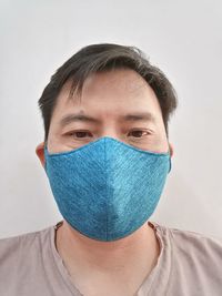 Portrait of teenage boy covering face against white background