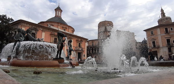 Water fountain in city against sky