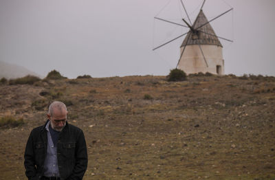 Adult man on fields against traditional windmill. cabo de gata nature park, almeria, spain