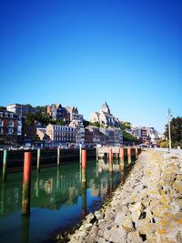 Buildings by river against blue sky