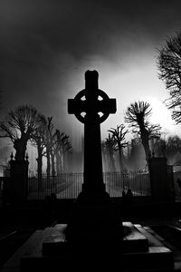 Cross in cemetery against sky