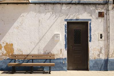 Empty bench by wall