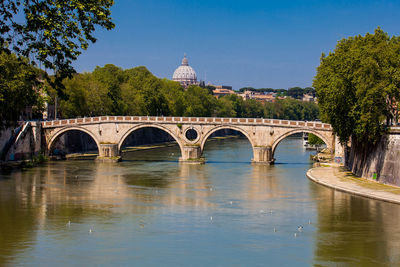 Arch bridge over river against clear sky