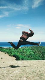 Young man jumping against sky