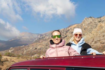 Low angle view of friends in sunglasses against mountain