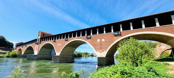 Arch bridge over river against sky