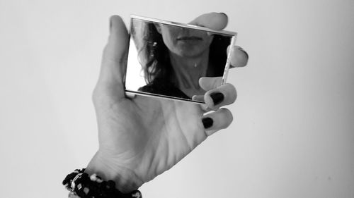 Midsection of person holding smart phone against white background