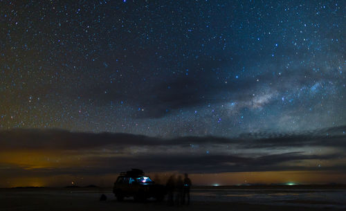 Blurred motion of people by off-road vehicle at salar de uyuni against constellation