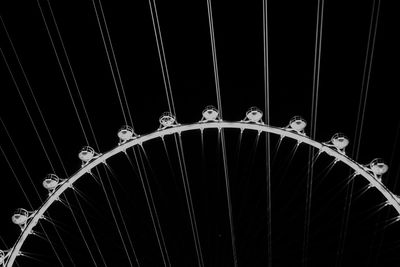 Low angle view of illuminated lighting equipment against black background