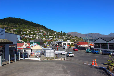 Road by buildings against clear blue sky