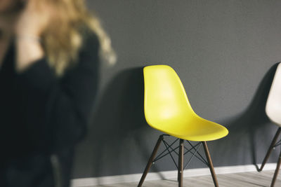 Empty yellow chair against black wall