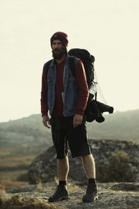 Full length of young man standing on mountain against clear sky