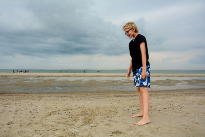 Full length of man standing on beach against sky