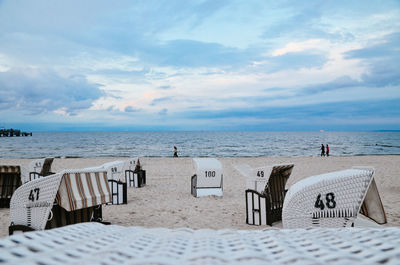 Hooded beach chairs by sea against sky