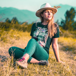 Young woman wearing hat sitting on field