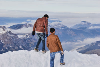 Rear view of people walking on snow covered mountain