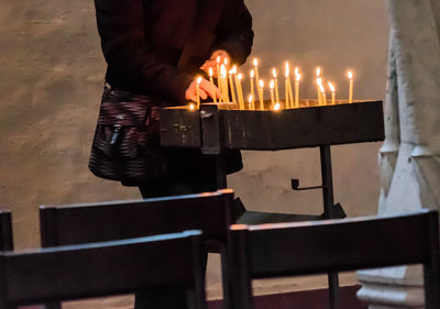 Midsection of man placing illuminated candle at church