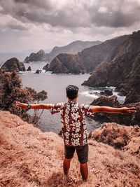 Rear view of person standing by mountains against sky