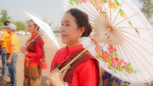 Woman holding traditional clothing standing outdoors