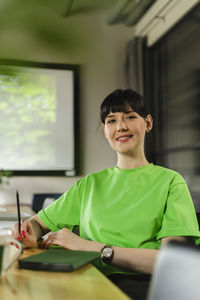 Smiling woman wearing green t-shirt sitting in office conference room