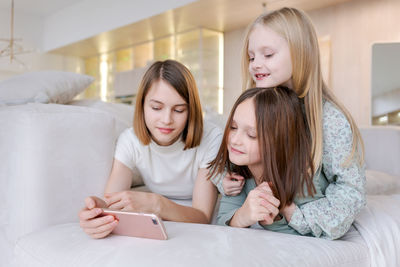 Young woman using digital tablet while sitting on bed at home