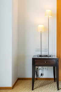 Electric lamp on table against wall at home